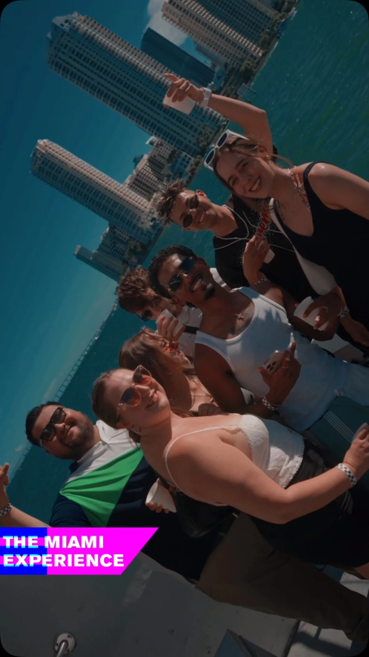 A group of friends enjoying The Miami Experience boat party with the Miami skyline behind them